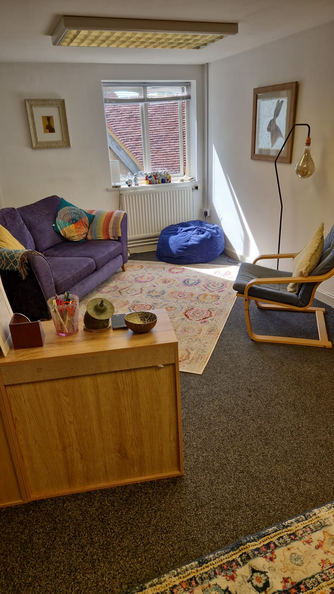 Interior of the therapy room at Anchor Point Psychotherapy — a calm, comfortable space with a sofa, armchair and soft lighting.